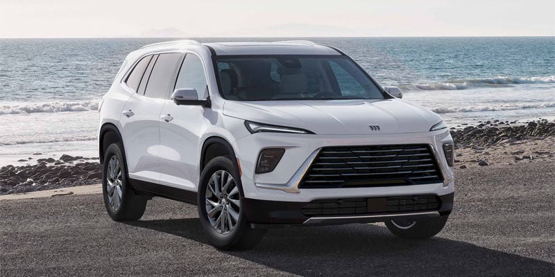 White Buick Enclave SUV parked near a beach with ocean views in the background