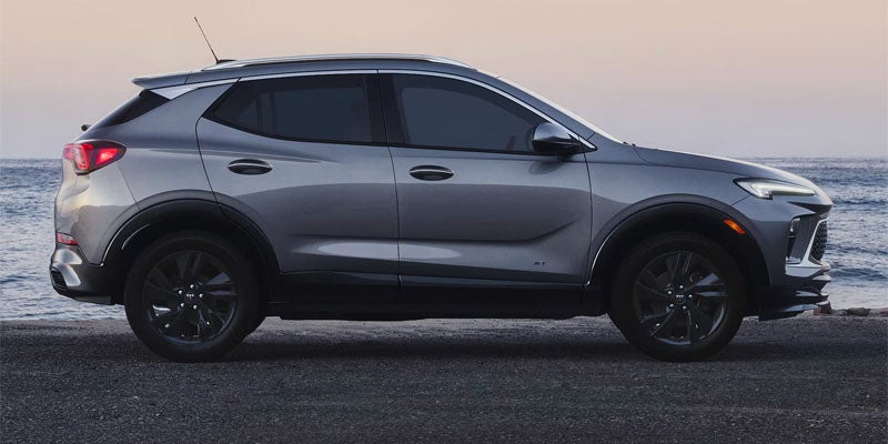 Side profile of a gray Buick SUV driving on a city road