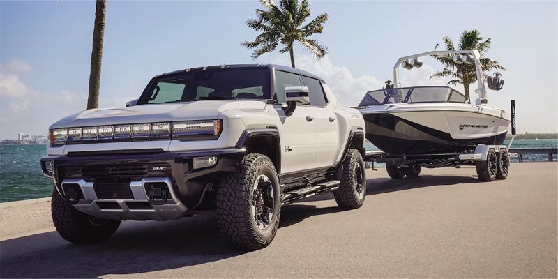 GMC Hummer EV pickup towing a boat by the water