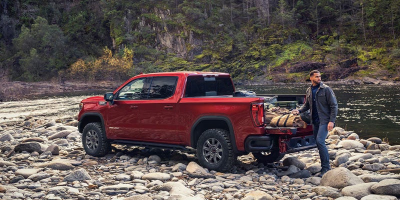Red GMC Sierra 1500 parked at a riverside campsite