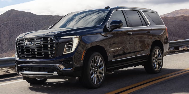 Dark GMC SUV driving on a road