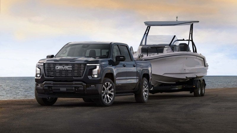 GMC Sierra 1500 towing a boat on a coastal road