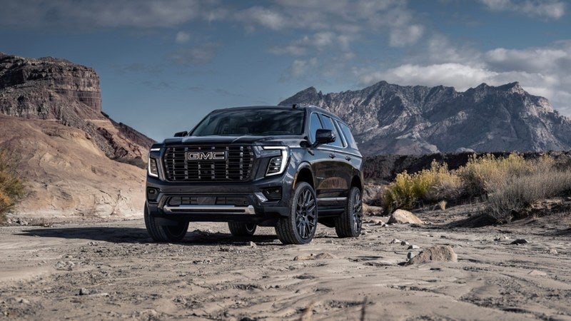 Black GMC Yukon Denali SUV in a mountain landscape